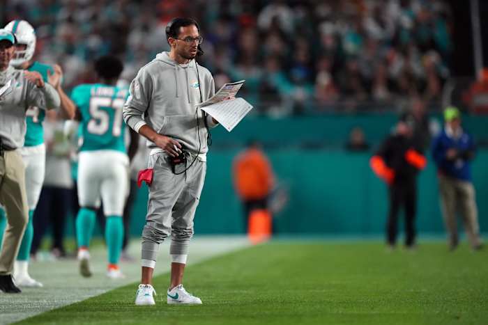 Mike McDaniel stands on the sideline looking at a piece of paper